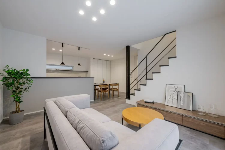 [LDK 全景] モルタル調の床と白い壁、アイアン手すりがつくる、ホテルライクで開放的なLDK空間