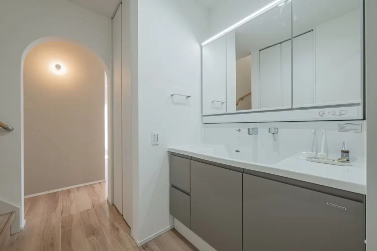 清潔感のある広々とした洗面化粧台。奥に見えるアーチ壁の開口が、シンプルな空間に可愛らしいアクセント。